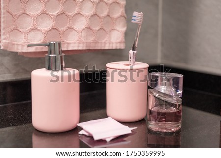 Pink hygienic amenities for bathroom : soap diffuser, sanitary napkins, parfume, towel, tooth brush, cream 