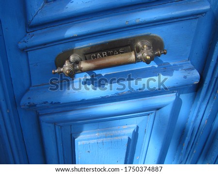 Old hardware, sign translation: "Letters". Mail box, on antique natural wood door with sky blue paint. Background for email web with natural texture and classic iron object illuminated by sunlight.