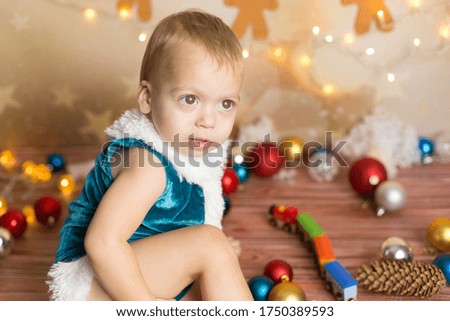 a little boy in a blue Christmas suit. a boy plays with a toy train