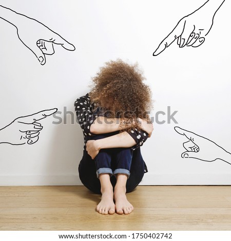 
young sad caucasian woman with red hair crying and pointed hands sitting against a wall inside a house