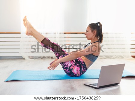 young woman doing yoga at home, online training via laptop