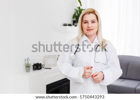 Smiling female doctor in white coat, on white