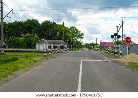 Empty railway crossing with a warning sign stop and a traffic light in a Ukrainian village. Copy space.