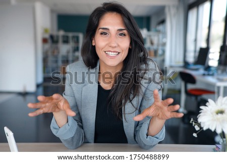 Shot of confident business woman looking and speaking through the webcam while making a video conference from the office. Royalty-Free Stock Photo #1750488899