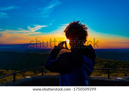 Rear view of a man photographing the sunset