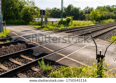 Empty railroad crossing in the countryside, on the road with open barriers. Royalty-Free Stock Photo #1750545116