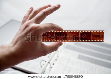 Film photography album for negative storing. A hand without gloves in the background, holding negatives. Different size negatives in special envelopes. 35mm and medium format photography.