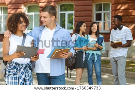 College Romance. Portrait of smiling male student cuddling his african american girlfriend outdoors during break in classes