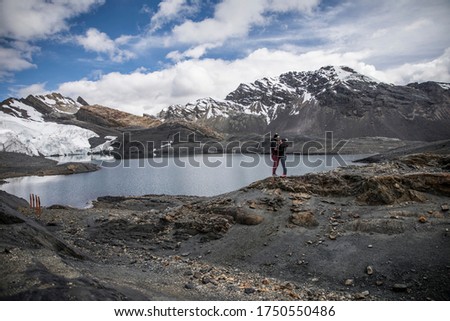 couple in a glacier, near a lake, mountains with snow in their peaks, clouds and blue sky