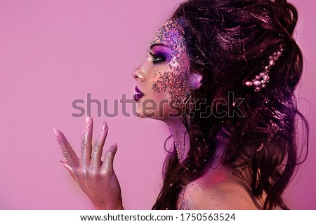 close up  portrait of young beautiful girl with colorful face painting. Halloween professional makeup. hair in paint. beauty portrait. colorful beads on face. profile