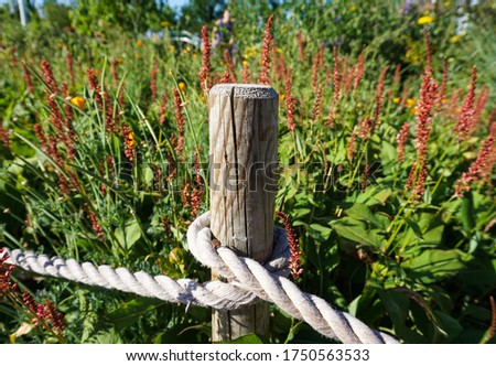 single wood fence with cross rope .flowers on background. guardian, protector concept