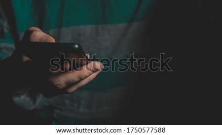 A guy with a phone in his hands on a black background. Concept of social networks and technologies.
