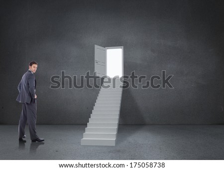 Serious businessman with hands on hips against open door at top of steps