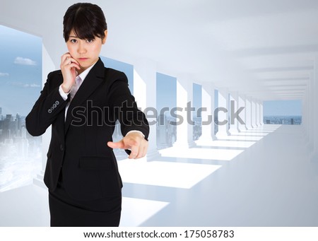 Thoughtful businesswoman pointing against bright white hall with columns