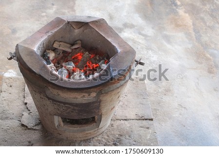 Burning charcoal with ashes in old charcoal stove clay earthenware for cooking with copy space close-up.