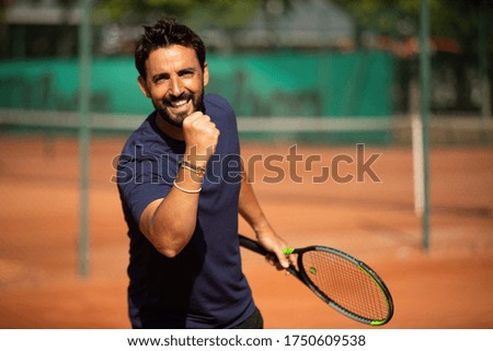a smiling man making the victory sign with his hand and playing tennis