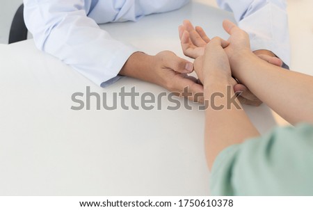 Asian orthopaedic doctor doing physical examination in the patient with wrist pain and numbness at the clinic. Pain from tendinitis and sport injury or repetitive use of computer. Medical concept.