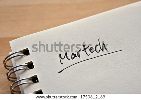 At the edge of the notebook, "Martech" is written. Close-up. It was coined by combining the words "Marketing" and "Technology".