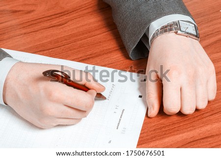 Men's hand fill out the tax return. Text in Russian: Declaration of an individual.