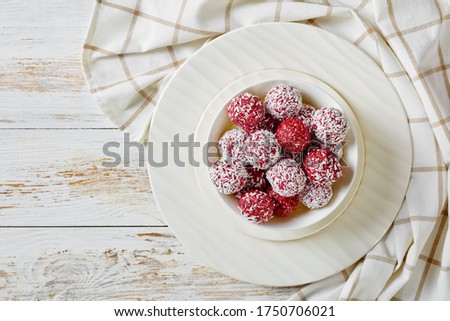 Berry bliss balls with peanut butter and chia seeds raspberries, blackberries, blueberries with chia seeds and desiccated coconut on a white plate on a white wooden background, top view, copy space Royalty-Free Stock Photo #1750706021