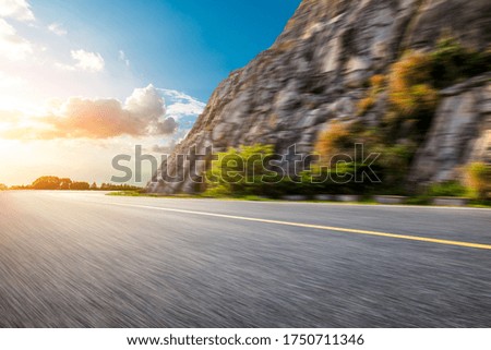 Motion blurred asphalt road and mountain landscape at sunset.