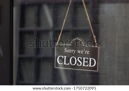 sorry we are closed sign hang on claer glass door of shop.