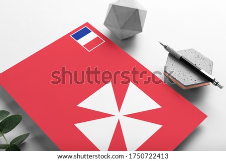 Wallis And Futuna flag on minimalist paper background. National invitation letter with stylish pen on stone. Communication concept.