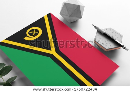Vanuatu flag on minimalist paper background. National invitation letter with stylish pen on stone. Communication concept.