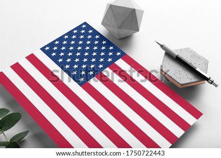 United States flag on minimalist paper background. National invitation letter with stylish pen on stone. Communication concept.