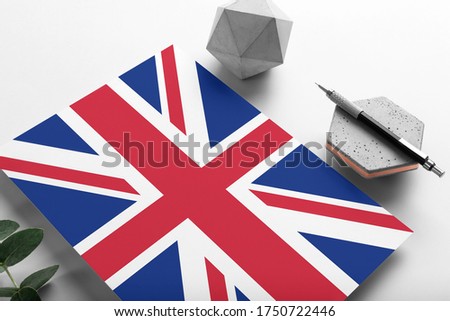 United Kingdom flag on minimalist paper background. National invitation letter with stylish pen on stone. Communication concept.