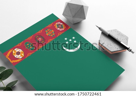 Turkmenistan flag on minimalist paper background. National invitation letter with stylish pen on stone. Communication concept.