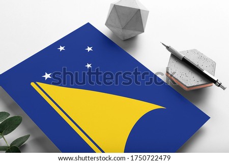 Tokelau flag on minimalist paper background. National invitation letter with stylish pen on stone. Communication concept.