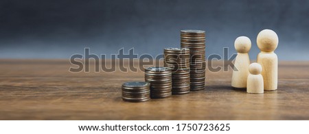 Many coins are stacked in a graph shape with family wooden doll for money saving ideas and financial planning insurance.