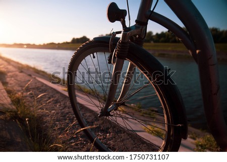A bicycle wheel standing by the river