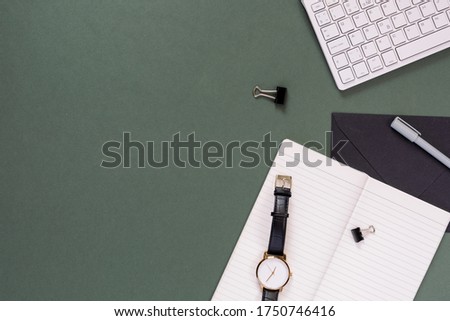 Top view of modern office desk with copy space. Empty weekly planner, keyboard, watch, stationery on pastel green background.