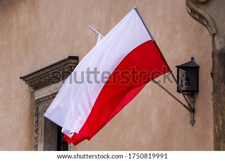 Red and white Polish flags hang on the house. Natural Light Selective Focus. building view. 1 of May, November 11, flag or independence or labor day. Government holiday Royalty-Free Stock Photo #1750819991