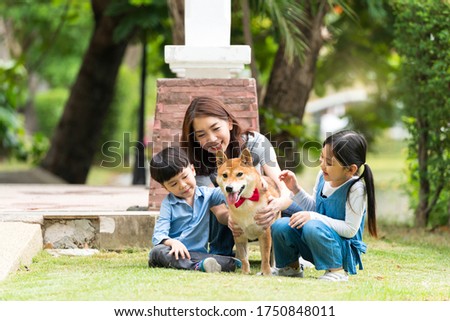 The family has a mother, daughter and son playing with Shiba Inu dogs In the park. An Asian family plays with a Shiba Inu dog has Picnicking in the garden. Royalty-Free Stock Photo #1750848011