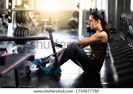 Female athlete taking rest after exercising at gym. Fitness Healthy lifestye and workout at gym concept.