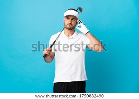 Young handsome man isolated on blue background playing golf and and having doubts confuse face expression