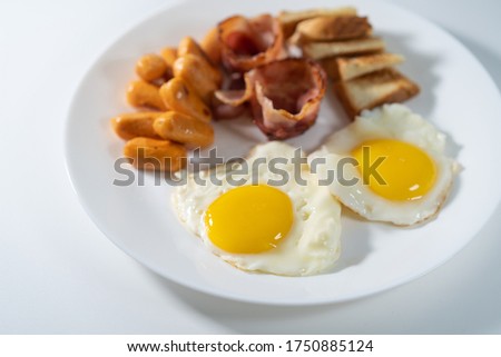 Western breakfast on isolated white background. Sunny side up eggs, sausage, bacon and toast bread. 