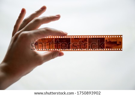 Film photography special envelope slips for negative storage. 35mm and medium format photography. A hand holding a film strip in front of white background.