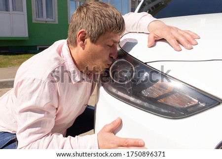 the Man kisses his new car in the headlight
