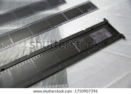 Film photography special envelope slips for negative storage. 35mm and medium format photography. Holding a film strip, putting it inside a scanner frame, preparing for scanning.