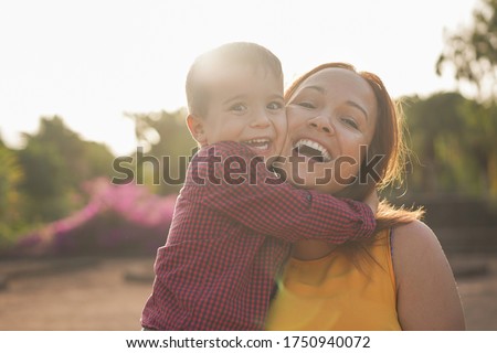 Happy young mother laughing with her son in her arms - Young mother and child in a nature park enjoy the time together - Mother and child love  Royalty-Free Stock Photo #1750940072