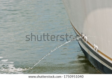Front view, medium distance of a power boat bilge pump, pumping water out of bilge into a tropical marina Royalty-Free Stock Photo #1750951040