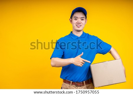 Asian delivery man holding parcel box over yellow isolate background. Work from home and delivery concept.