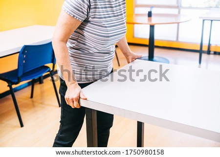 Move and adapt tables in a school academy so that students maintain a safe distance. Reopening and adaptation of schools and academies to the new normal. Royalty-Free Stock Photo #1750980158