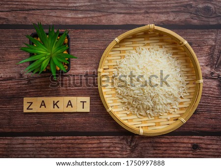 Conceptual zakat (islamic tax) with rice. Obligation to aid the poors. ZAKAT text on wooden table. Islamic zakat concept. Selective focus.