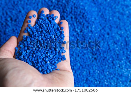 Blue plastic grain, plastic polymer granules,hand hold Polymer pellets, Raw materials for making water pipes, Plastics from petrochemicals and compound extrusion, resin from plant polyethylene. Royalty-Free Stock Photo #1751002586