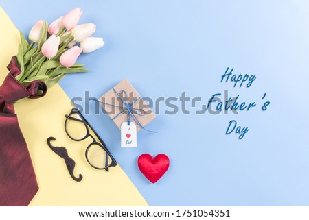 Happy Fathers Day background concept.Decorated red necktie, tulip, red heart, mustache, eyeglasses, gift box with greeting card on bright pastel background with copy space. Top view, flat lay.